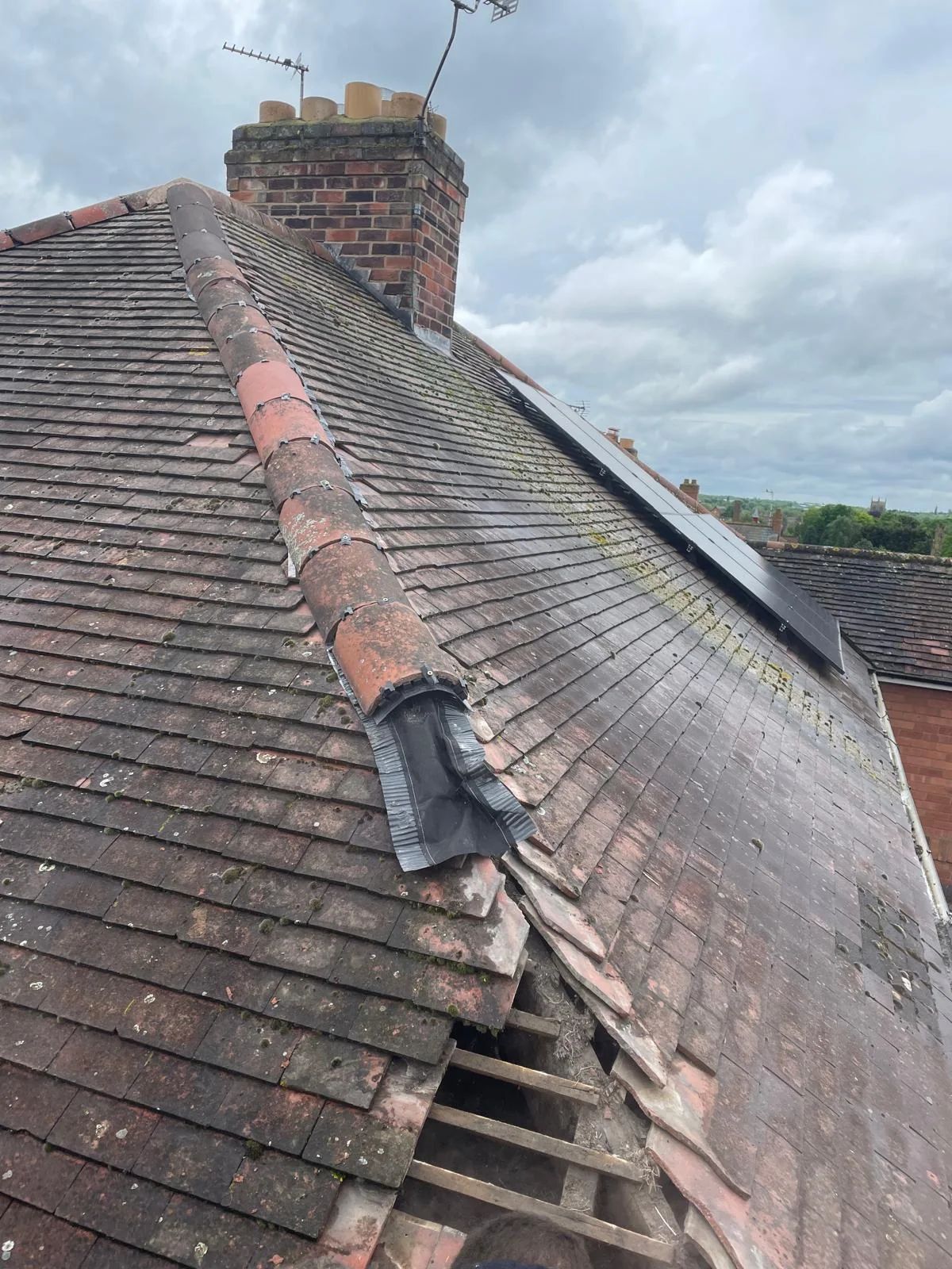 Tiled roof ridge with missing and broken ridge tiles before repair