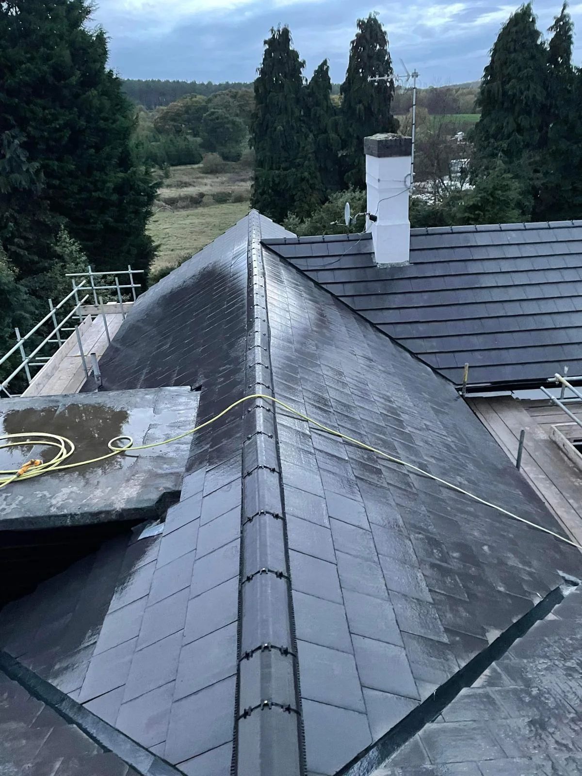 Dark slate roof with a new hip ridge, part-way through the job with scaffolding